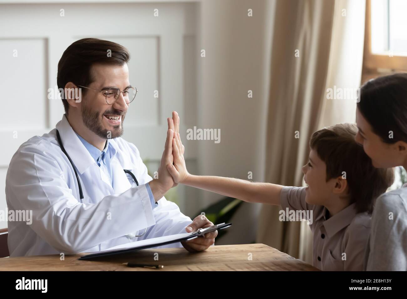 Joyeux médecin de sexe masculin encourager un petit garçon lors de la consultation Banque D'Images