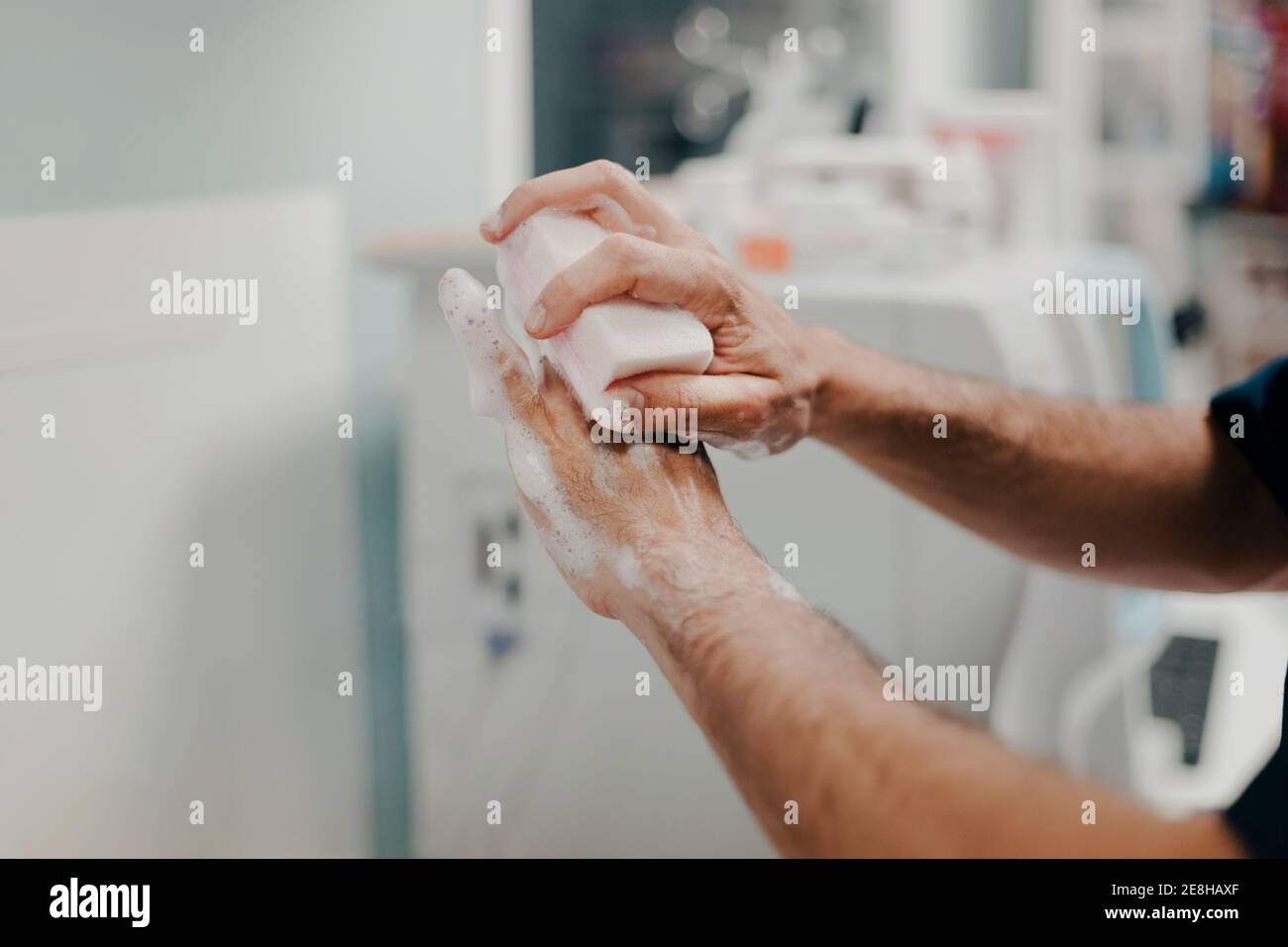Vue de côté de récolte d'un médecin masculin méconnaissable se désinfecte les mains à l'intérieur hôpital Banque D'Images