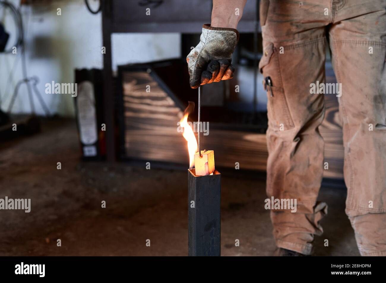 Crop anonyme tatoué forgeron masculin dans des vêtements décontractés et un  tablier chauffer les pinces métalliques à la flamme pendant le processus de  forgeage en atelier Photo Stock - Alamy