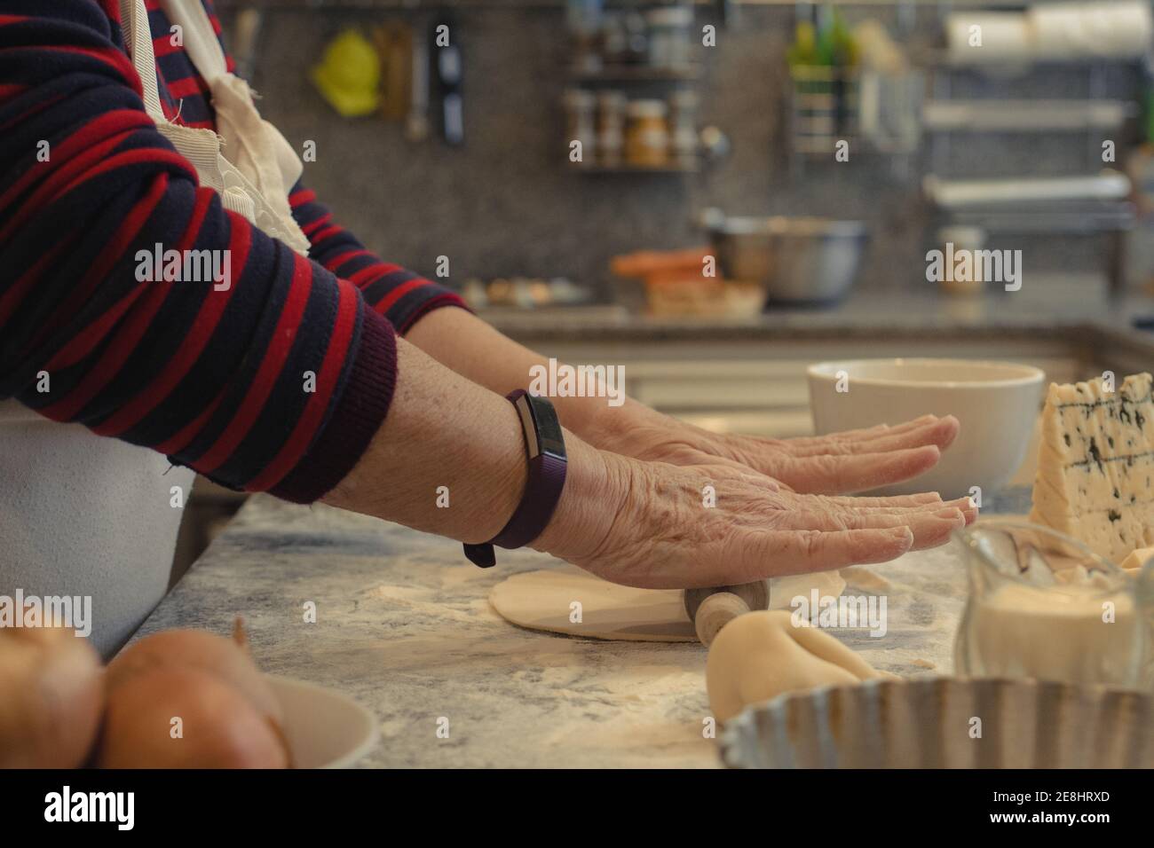 Du dessus de la récolte, les personnes âgées méconnaissables cuisent la croûte en roulant sur la table avec de la farine tout en cuisinant dans la cuisine à la maison Banque D'Images