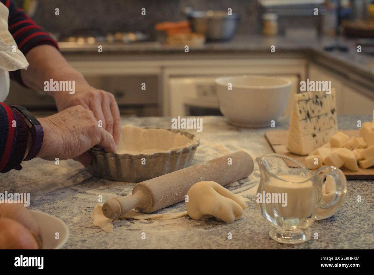 Crop anonyme chef avec pâte au-dessus de la table avec la cuisson plat et assortiment de fromages pendant la cuisson Banque D'Images