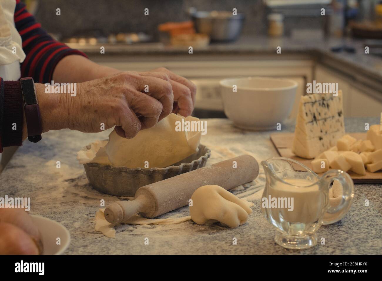 Crop anonyme chef avec pâte au-dessus de la table avec la cuisson plat et assortiment de fromages pendant la cuisson Banque D'Images