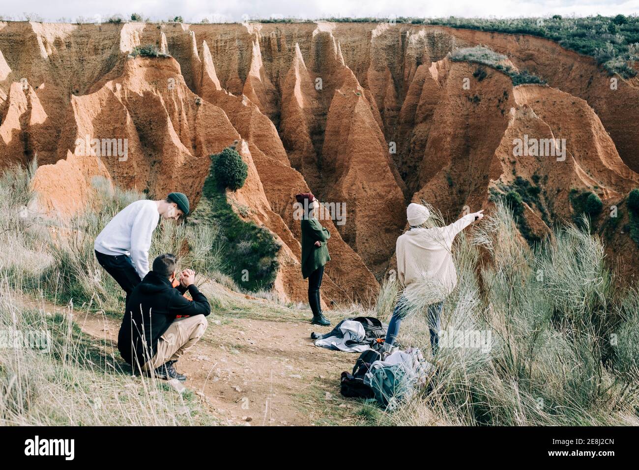 Une femme imreconnaissable qui pointe vers la gorge près d'amis qui parlent Terrain sec avec herbe pendant le voyage en Espagne Banque D'Images