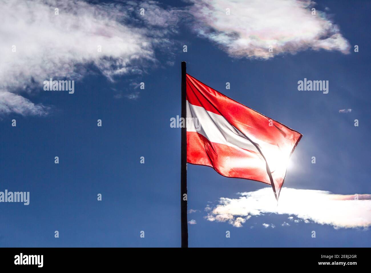 Drapeau agitant de l'Autriche rétroéclairé par le soleil et avec ciel bleu en arrière-plan Banque D'Images