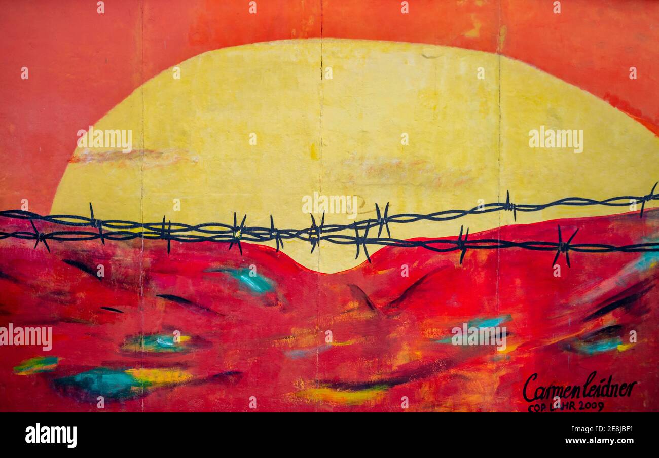 Peinture murale Niemandsland par Carmen Leidner, murale avec fil barbelé devant le soleil couchant, mur de Berlin, East Side Gallery, Berlin, Allemagne Banque D'Images