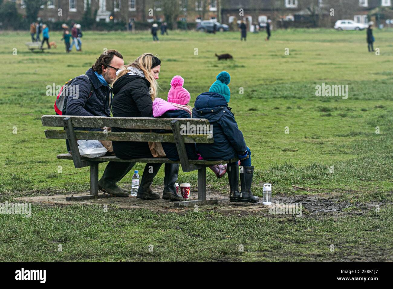 WIMBLEDON LONDRES, ROYAUME-UNI 31 JANVIER 2021. Une famille assise sur un banc . Malgré le temps froid et les températures glaciales, de nombreuses personnes marchent avec leurs chiens ou avec leurs familles et leurs amis sur Wimbledon Common lors du troisième confinement. Le gouvernement a conseillé aux gens de rester à la maison pour freiner la propagation de la nouvelle variante COVID-19 afin d'alléger la pression sur le crédit NHS: amer ghazzal/Alamy Live News Banque D'Images