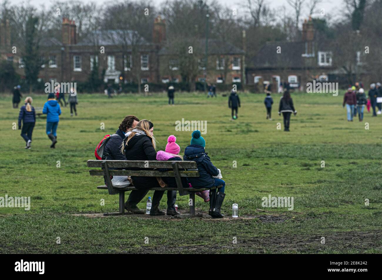 WIMBLEDON LONDRES, ROYAUME-UNI 31 JANVIER 2021. Une famille assise sur un banc. Malgré le temps froid et les températures glaciales, de nombreuses personnes marchent avec leurs chiens ou avec leurs familles et leurs amis sur Wimbledon Common lors du troisième confinement. Le gouvernement a conseillé aux gens de rester à la maison pour freiner la propagation de la nouvelle variante COVID-19 afin d'alléger la pression sur le crédit NHS: amer ghazzal/Alamy Live News Banque D'Images