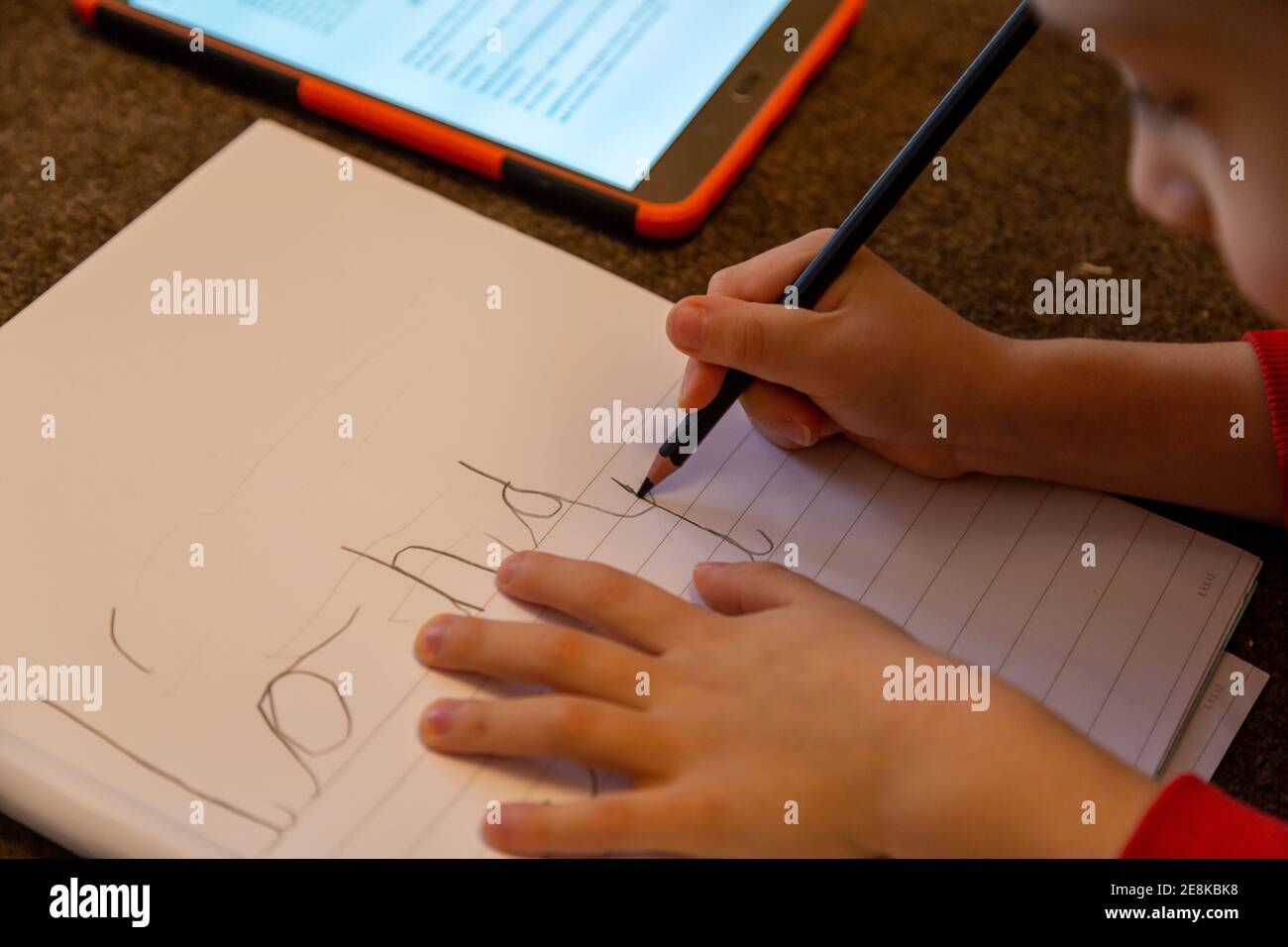 Un enfant apprenant à écrire sur papier ligné Banque D'Images