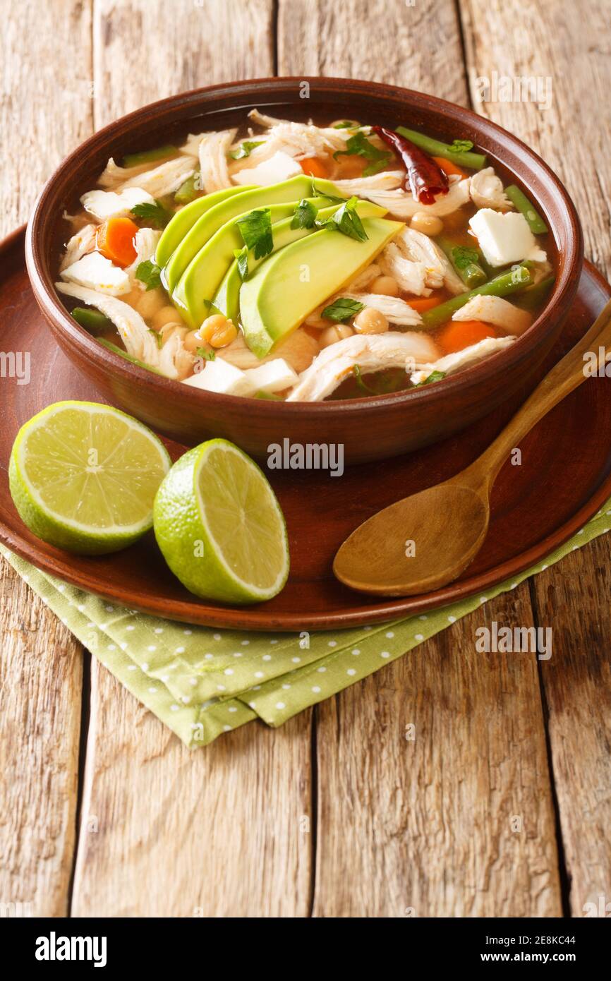 Soupe mexicaine de caldo tlalpeno, faite avec du bouillon de poulet maison, une base de tomate chipotle et un poulet râpé dans l'assiette sur la table. Vertica Banque D'Images