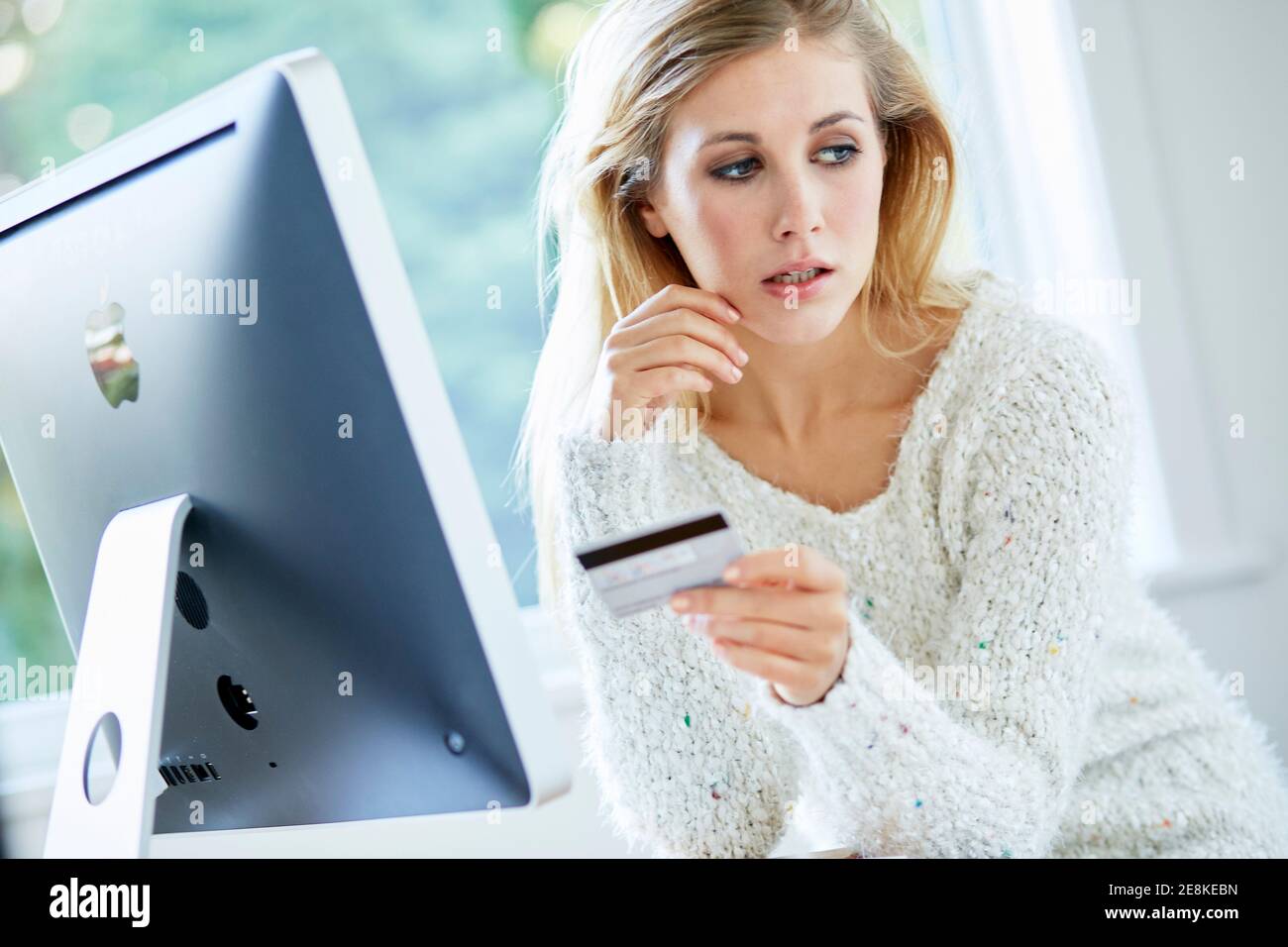 Femme tenant sa carte de crédit achetant des articles en ligne Banque D'Images