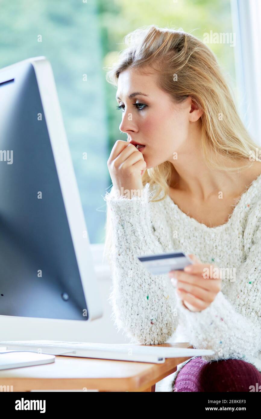 Femme tenant sa carte de crédit achetant des articles en ligne Banque D'Images