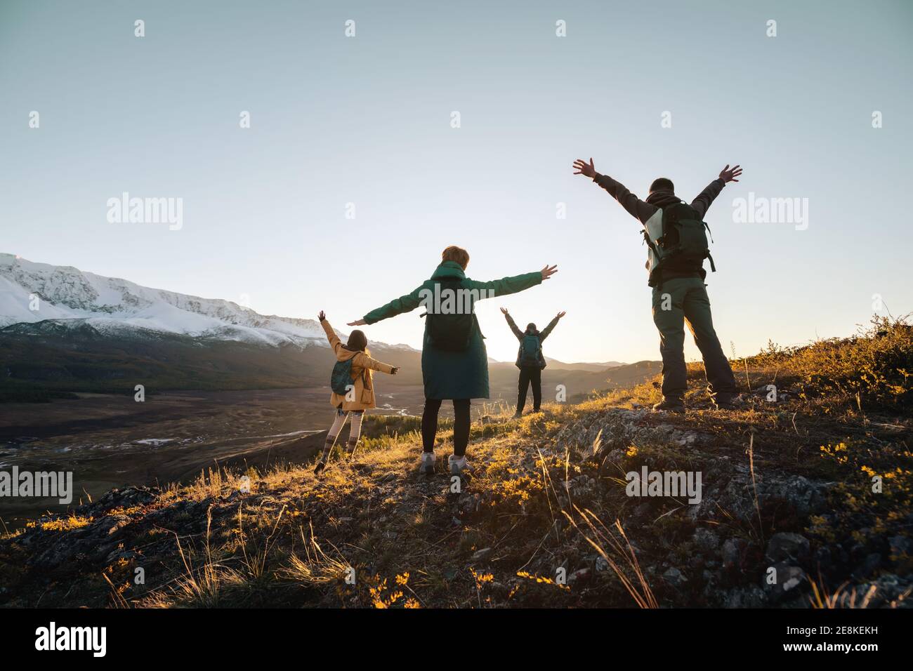 Les randonneurs heureux se tient avec les bras levés et regardant le coucher du soleil montagnes Banque D'Images