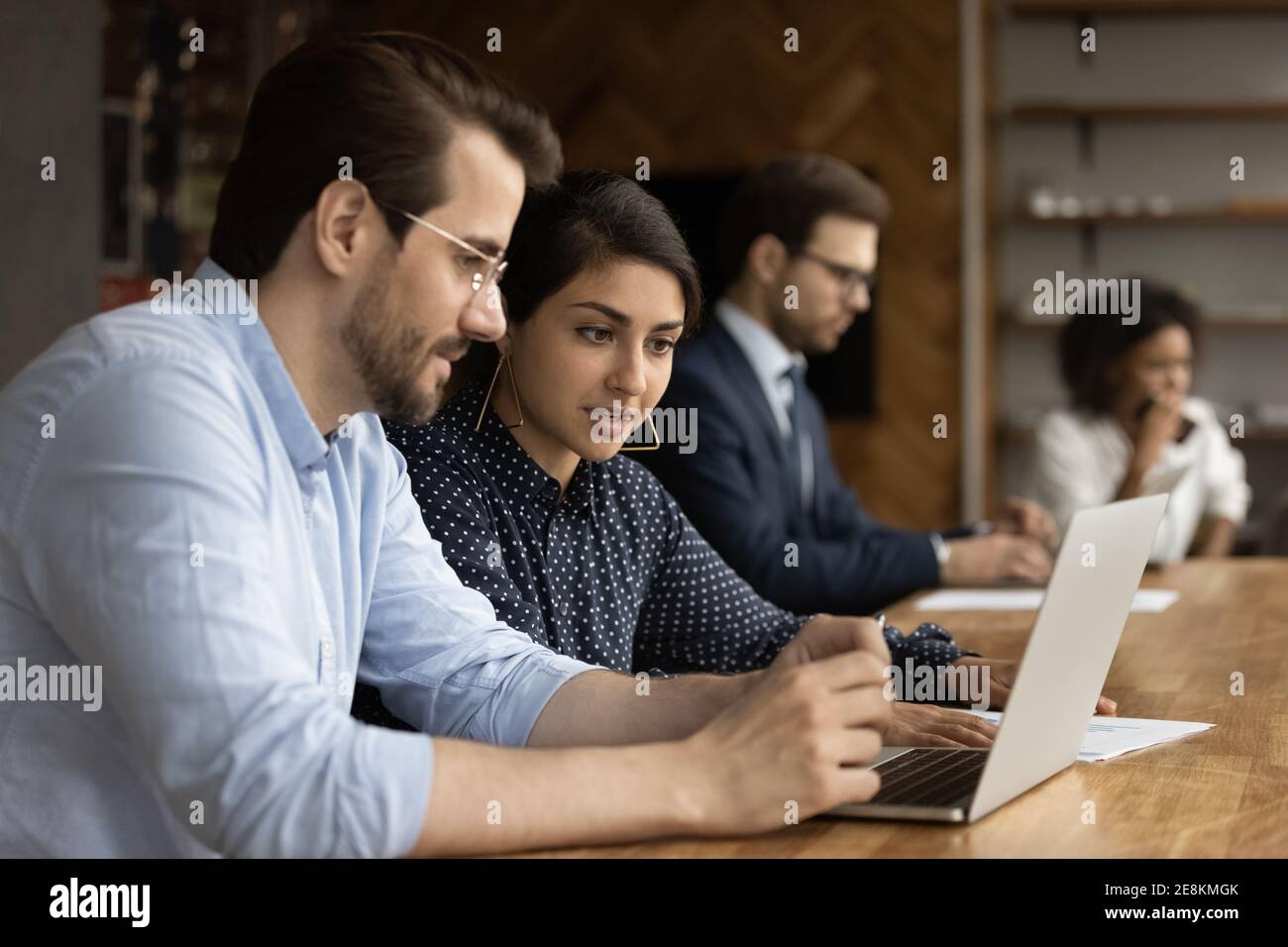 Une femme hindoue travailleuse expérimentée aide un jeune employé dans le travail d'ordinateur Banque D'Images