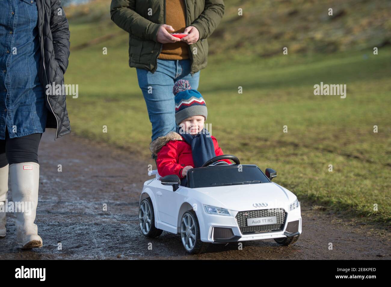 Hamilton, Écosse, Royaume-Uni. 31 janvier 2021. Photo : une jeune famille voit marcher pendant que son enfant prend les sites de sa voiture Audi convertible jouet dans le parc. Les gens dehors dans le parc de campagne de Chatelherault prenant l'exercice que la température reste juste au-dessus de zéro. Le soleil est dehors et les gens s'amusent pendant le verrouillage de phase 4 du coronavirus. Crédit : Colin Fisher/Alay Live News Banque D'Images