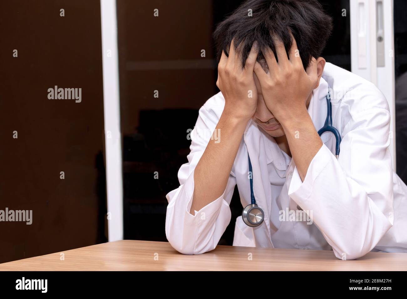 Un médecin a mis sa main sur sa tête comme il a été stressé. Médecin surtravaillé assis à l'hôpital. Parce qu'il travaille trop dur. Banque D'Images