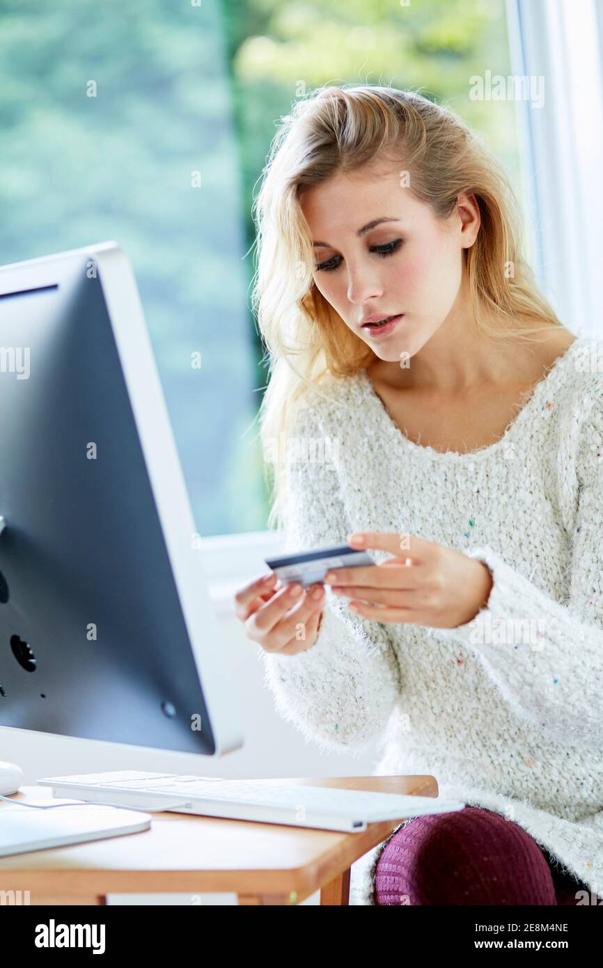 Femme tenant sa carte de crédit achetant des articles en ligne Banque D'Images