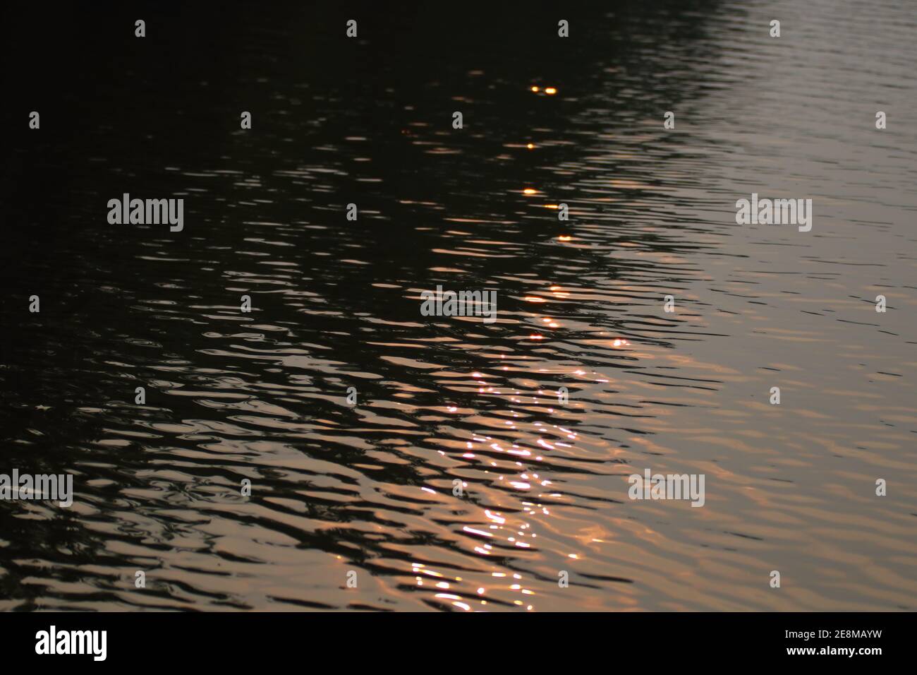 les reflets du coucher de soleil dans l'eau créent un motif abstrait Banque D'Images