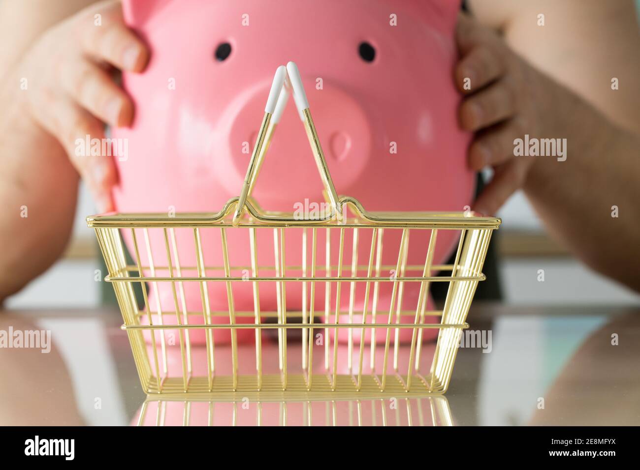 l'homme a une grande banque de porc dans ses mains, un panier doré se tient sur la table en face d'eux. Le concept de l'économie Banque D'Images