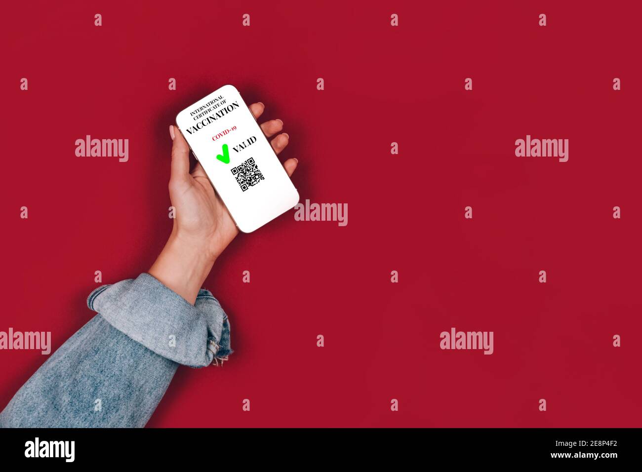 La main de la femme tient un smartphone avec un certificat de vaccination numérique valide - Passeport numérique de vaccination pour COVID-19 sur fond rouge avec Banque D'Images