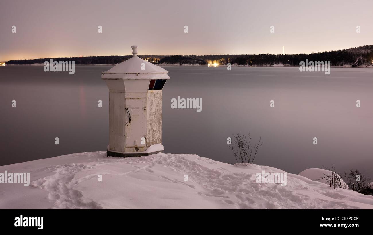 Phare blanc sur la côte de Bogesundslandet en direction de Lidingö, en Suède, près de Stockholm, pendant une nuit d'hiver Banque D'Images