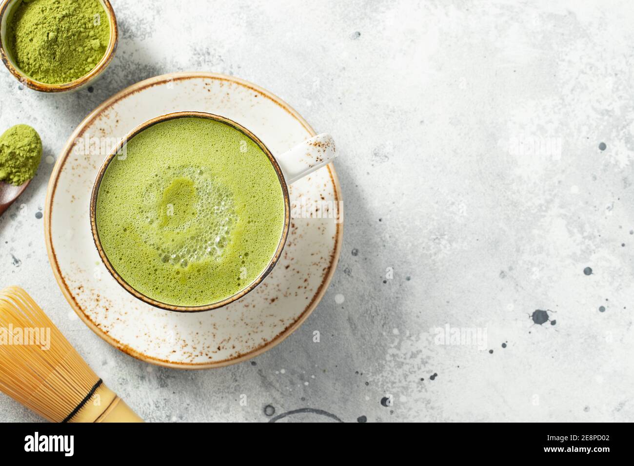 Latte de thé vert de Matcha dans une tasse avec de la crème sur un fond de béton léger. Vue de dessus avec espace de copie. Banque D'Images
