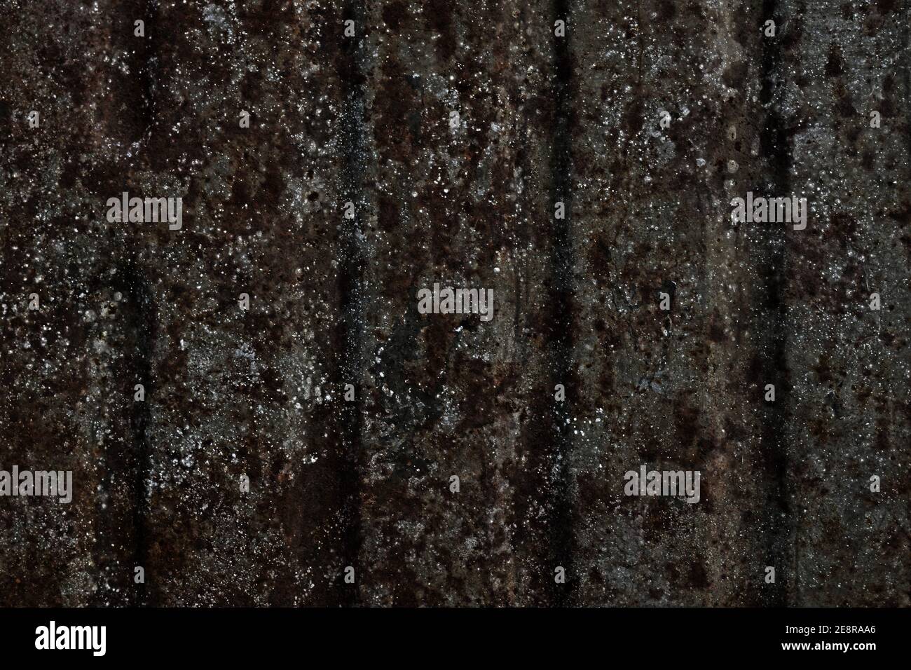 Surface avec de grandes bandes rouillées de taches brunes homogènes et de taches argentées sur fond gris acier avec rainures verticales. Banque D'Images