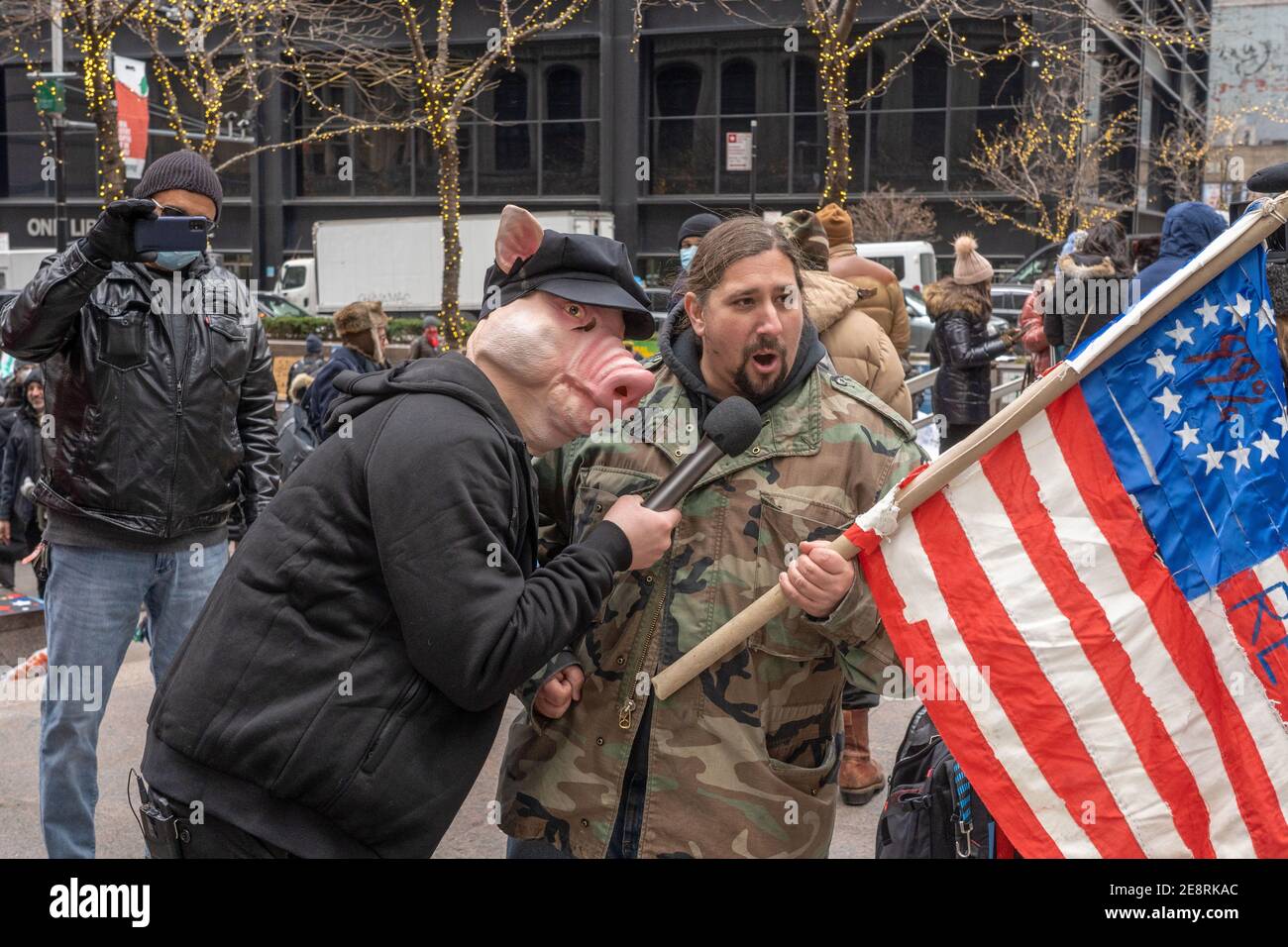 NEW YORK, NY - JANVIER 31 : un homme portant un masque de porc et un uniforme de police a interviewé un manifestant détenant un drapeau américain de 99 % lors de la manifestation « Re-Occupy Wall Street » au sujet de la controverse sur les actions GameStop à Zuccotti Park le 31 janvier 2021 à New York. Plusieurs dizaines de membres du New York Young Républicains Club se sont réunis dans le Zuccotti Park de Manhattan pour protester contre les gestionnaires de fonds spéculatifs de Wall Street, qui ont pris des positions pour arrêter la course « Little Guy » de Reddit sur le stock du vendeur de jeux vidéo pour le consolider après que les hommes aient misé sur le tanking. Banque D'Images