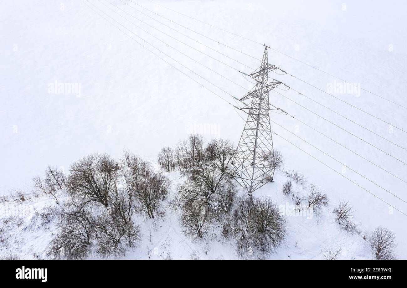 pylône haute tension sur la côte du lac gelé en hiver, par une journée de brouillard. vue aérienne Banque D'Images