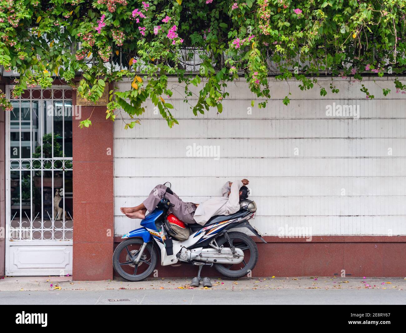 Chauffeur de moto se reposant dans un petit coin de rue dans le quartier résidentiel de Ho Chi Minh ville, Vietnam. Les ruelles comme celle-ci, trop étroites pour les voitures, sont très Banque D'Images