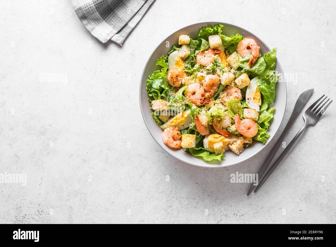 Salade de crevettes. Salade César aux fruits de mer sur fond de pierre grise, vue du dessus, espace copie. Banque D'Images