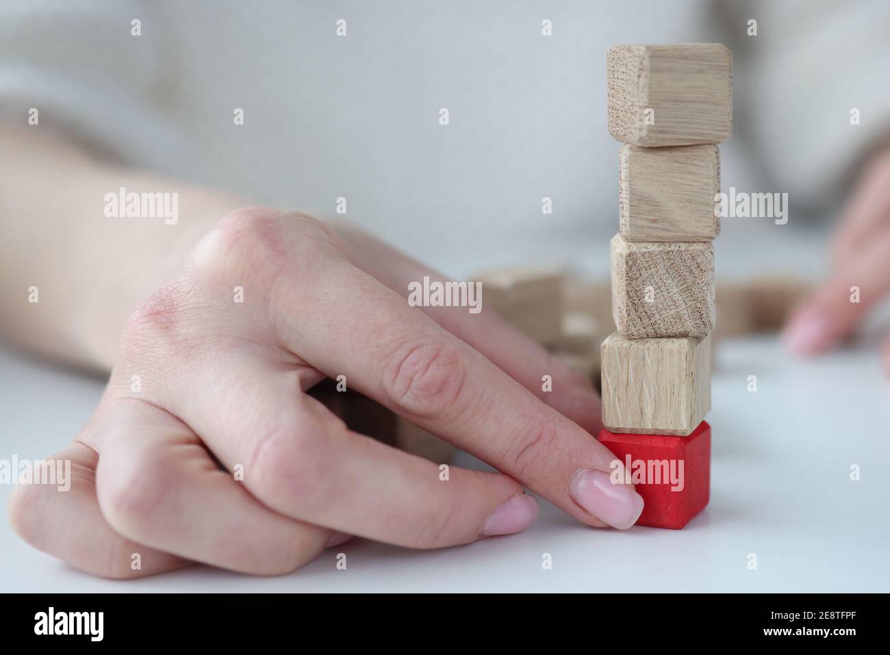 Main femelle tirant le cube en bois rouge de la base de vue rapprochée de la tour Banque D'Images