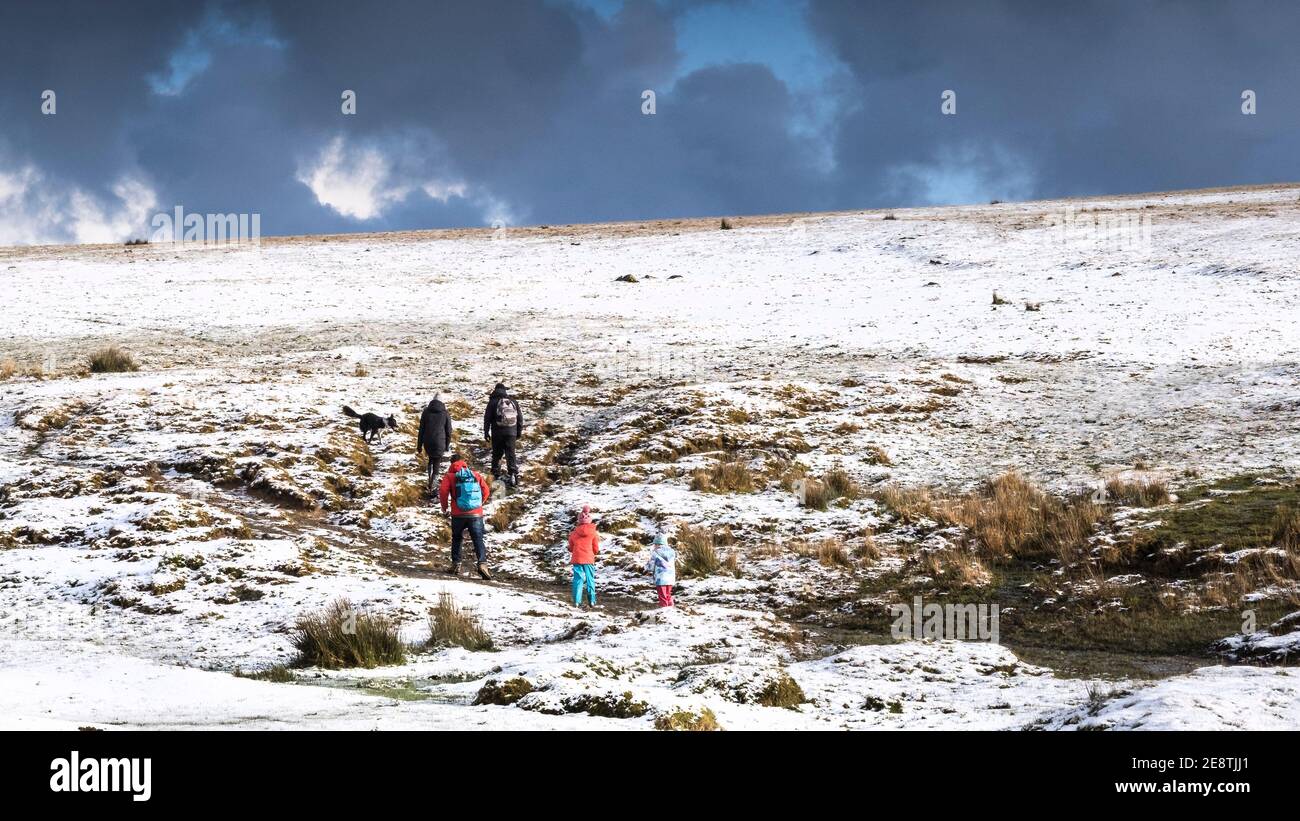 Une vue panoramique d'une famille en profitant d'une promenade dans la neige sur la sauvage sauvage robuste Tor Rough sur Bodmin Moor dans les Cornouailles. Banque D'Images