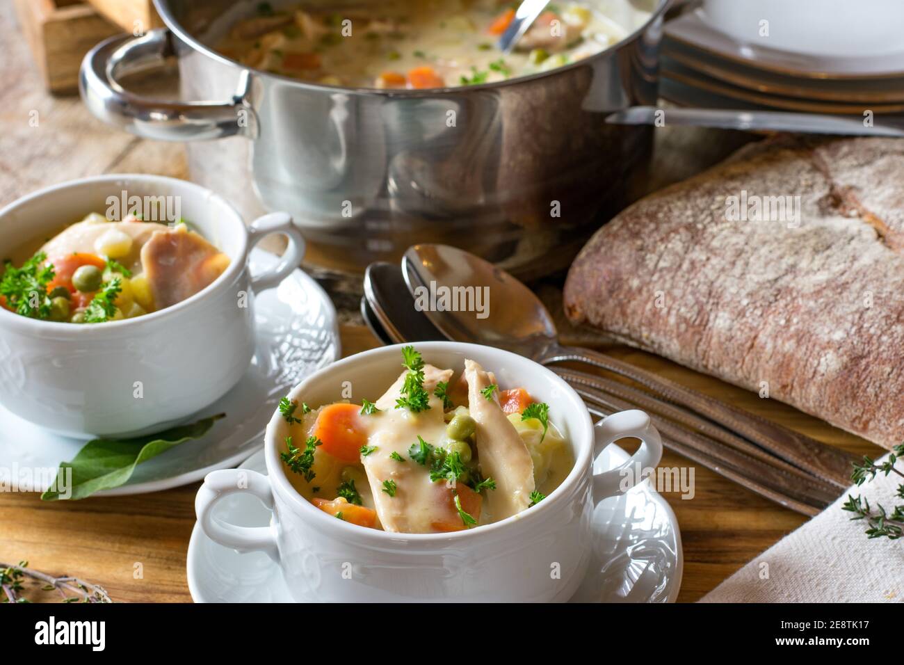 crème de poulet servie dans des bols à soupe avec pot et des cuillères sur une table Banque D'Images