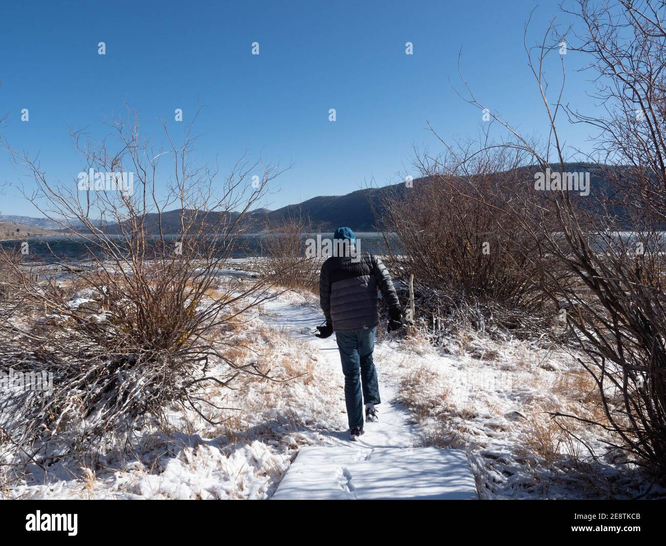Garçon marchant vers le lac dans la parka dans la forêt nationale de Fishlake, Richfield, Utah en hiver, fin de l'automne par temps froid clair avec de la neige Banque D'Images