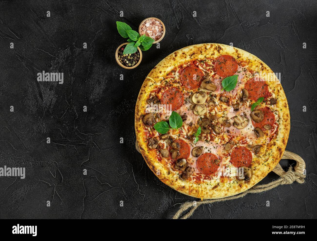 Pizza italienne chaude à Naples avec jambon et champignons à l'obscurité arrière-plan Banque D'Images
