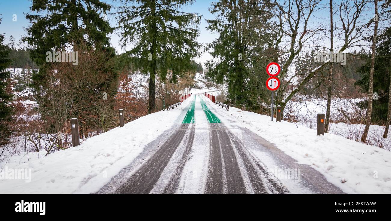 Route enneigée et pont étroit à Butgenbach, Ardennes, Belgique. Banque D'Images