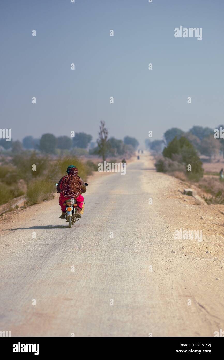 Deux villageois en vélo dans la zone de la règle passant par l'agriculture champ Banque D'Images