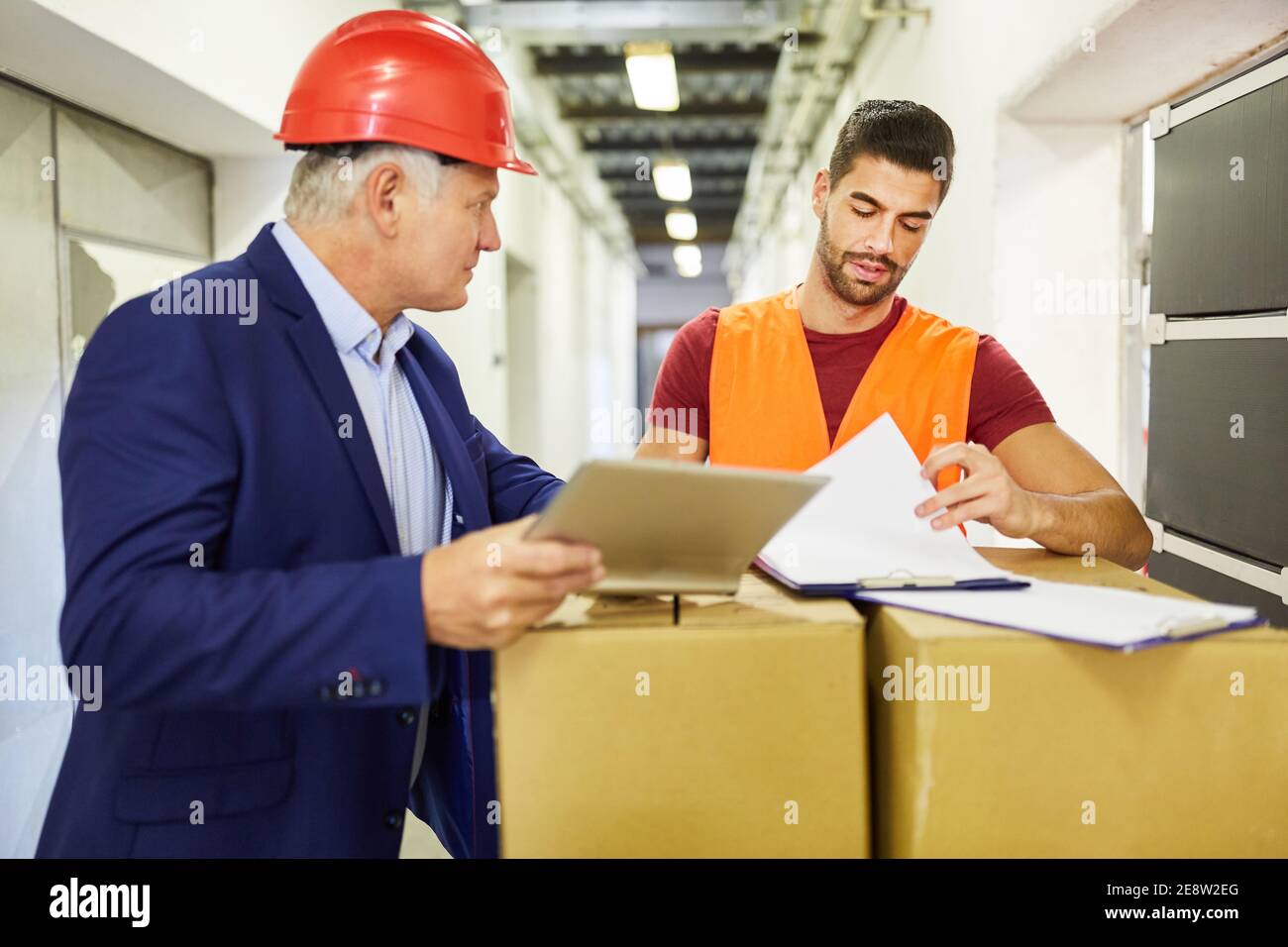 Le commis de l'entrepôt et le contremaître vérifient la livraison des marchandises avec un liste de contrôle et ordinateur Banque D'Images