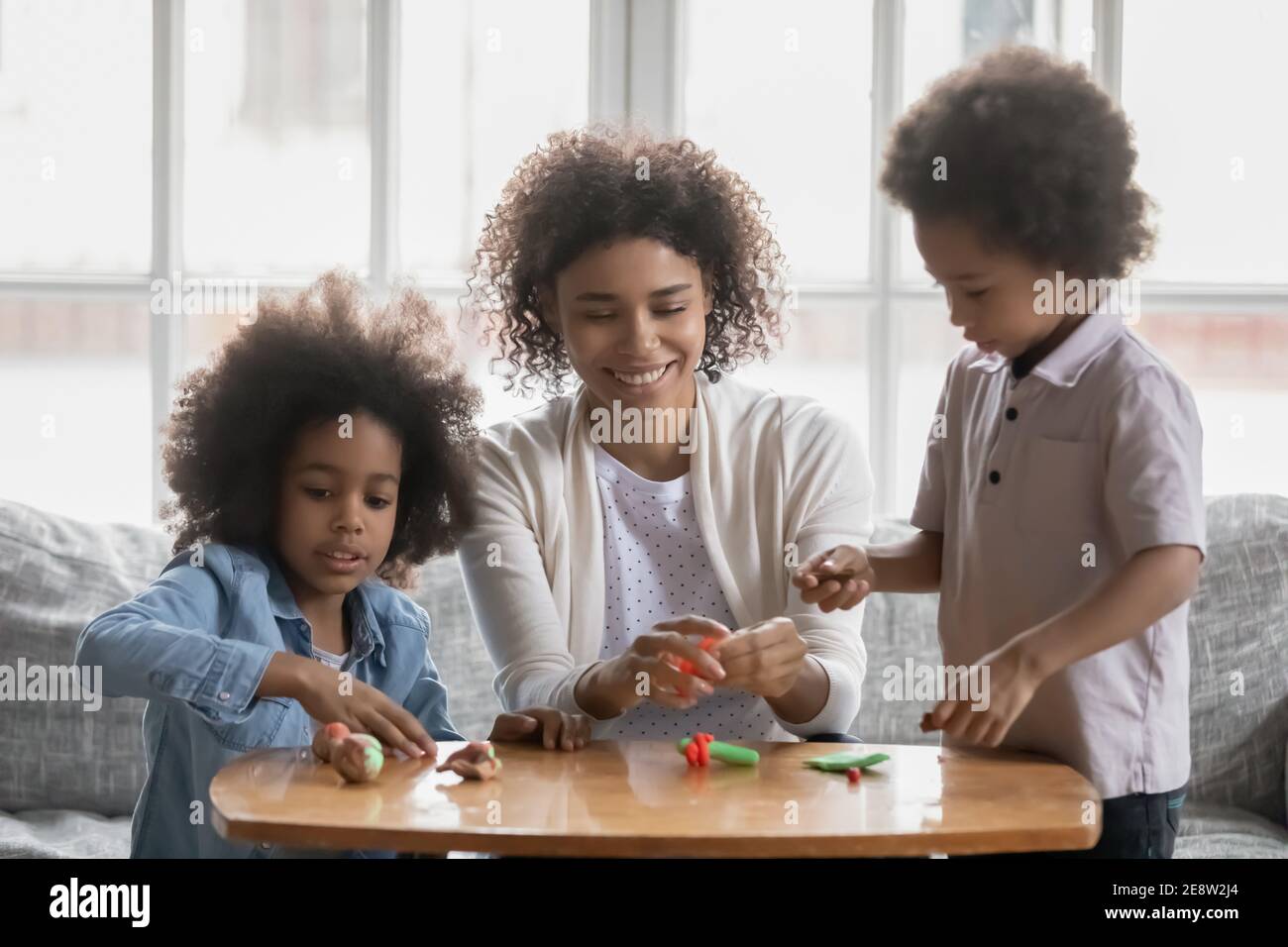 Bonne femme afro-américaine avec et enfants jouant avec la plasticine Banque D'Images