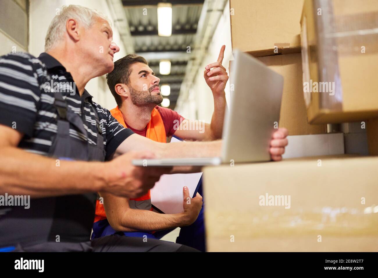 Deux employés d'entrepôt sur ordinateur portable avec colis avant expédition dans les affaires en ligne Banque D'Images