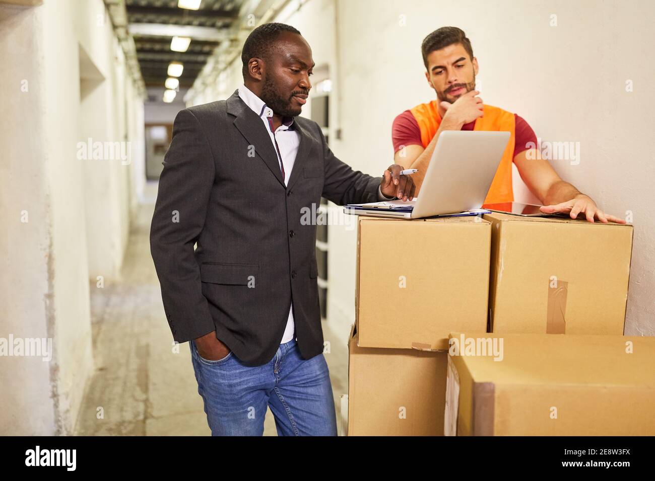 Entrepreneur et employé d'entrepôt sur ordinateur portable avec colis lors de l'expédition dans le commerce en ligne Banque D'Images