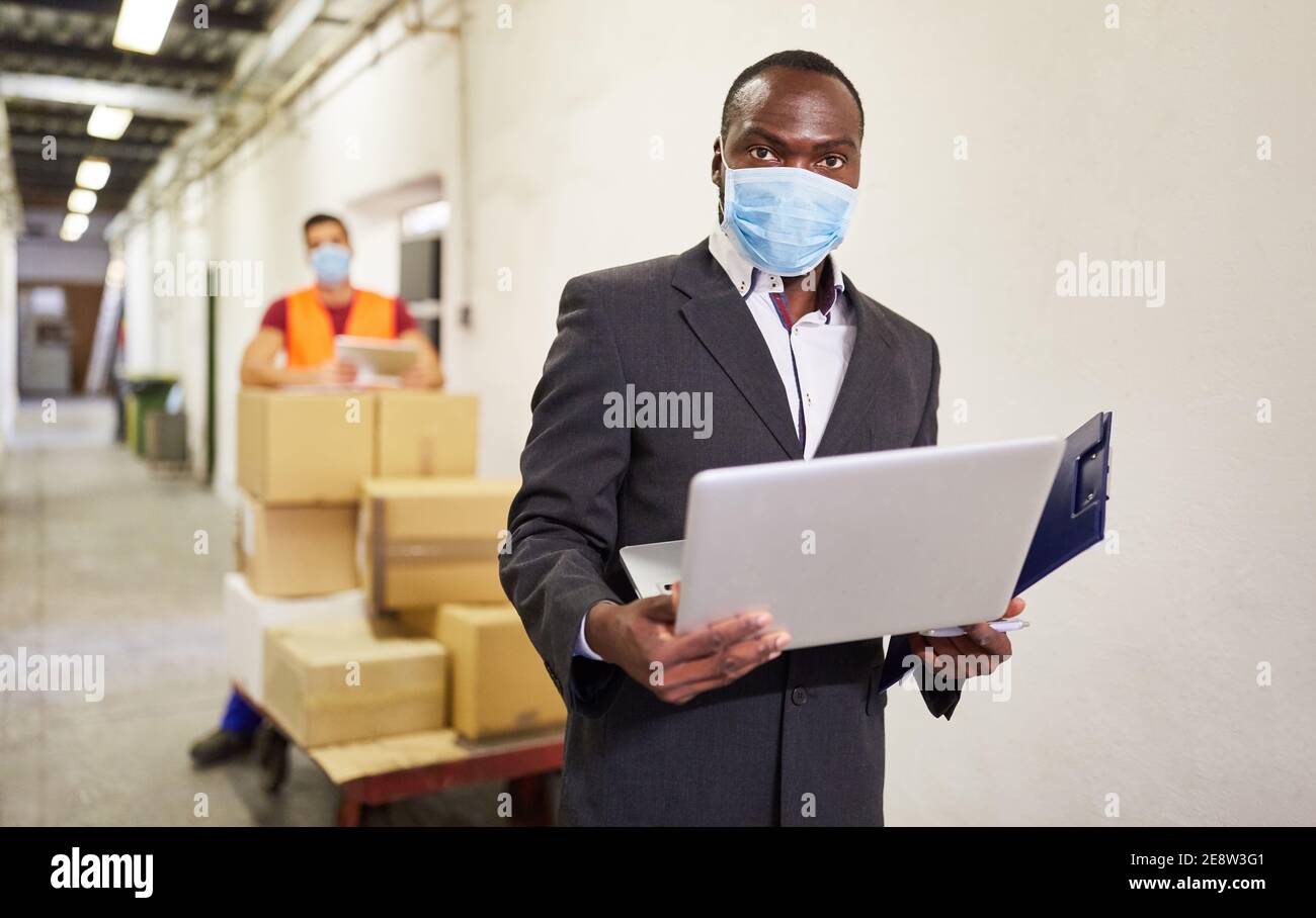 Homme d'affaires africain avec masque facial et ordinateur portable en ligne entreprise Banque D'Images