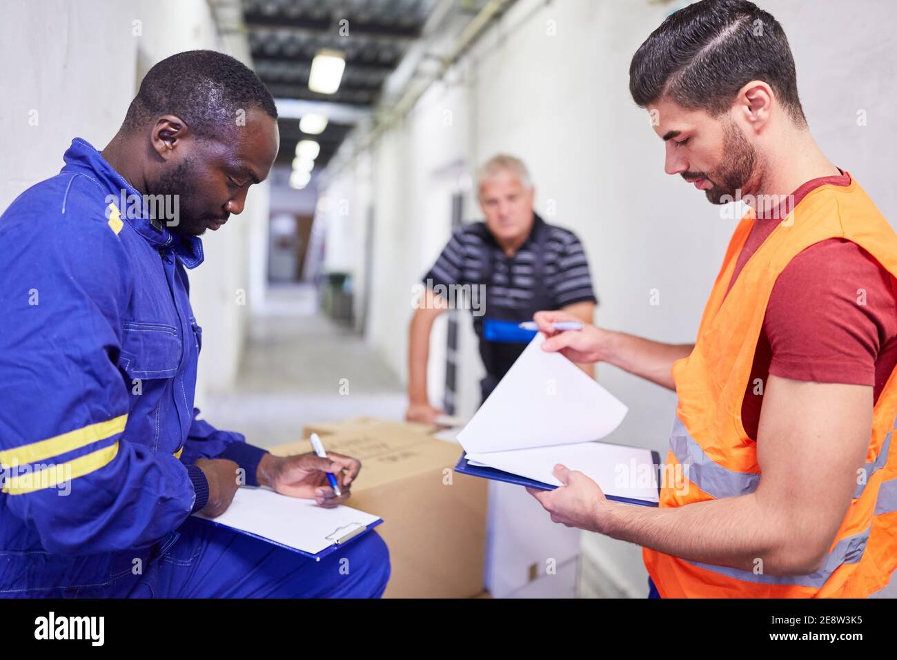 L'employé de l'entrepôt vérifie la livraison des marchandises avec la liste de vérification sur le presse-papiers à marchandises entrantes Banque D'Images