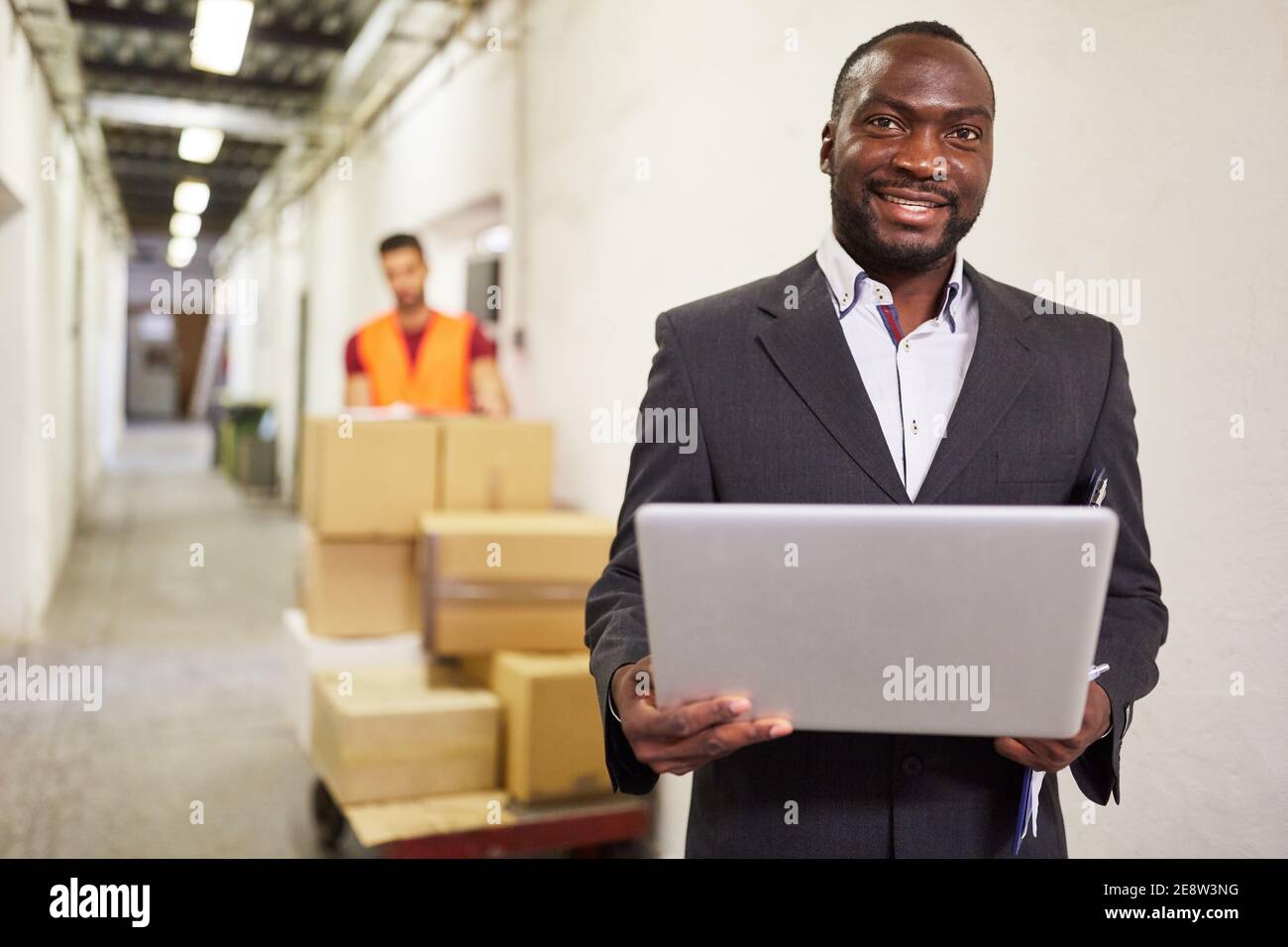 Homme d'affaires africain dans l'entrepôt utilisant ordinateur portable dans les affaires en ligne Banque D'Images