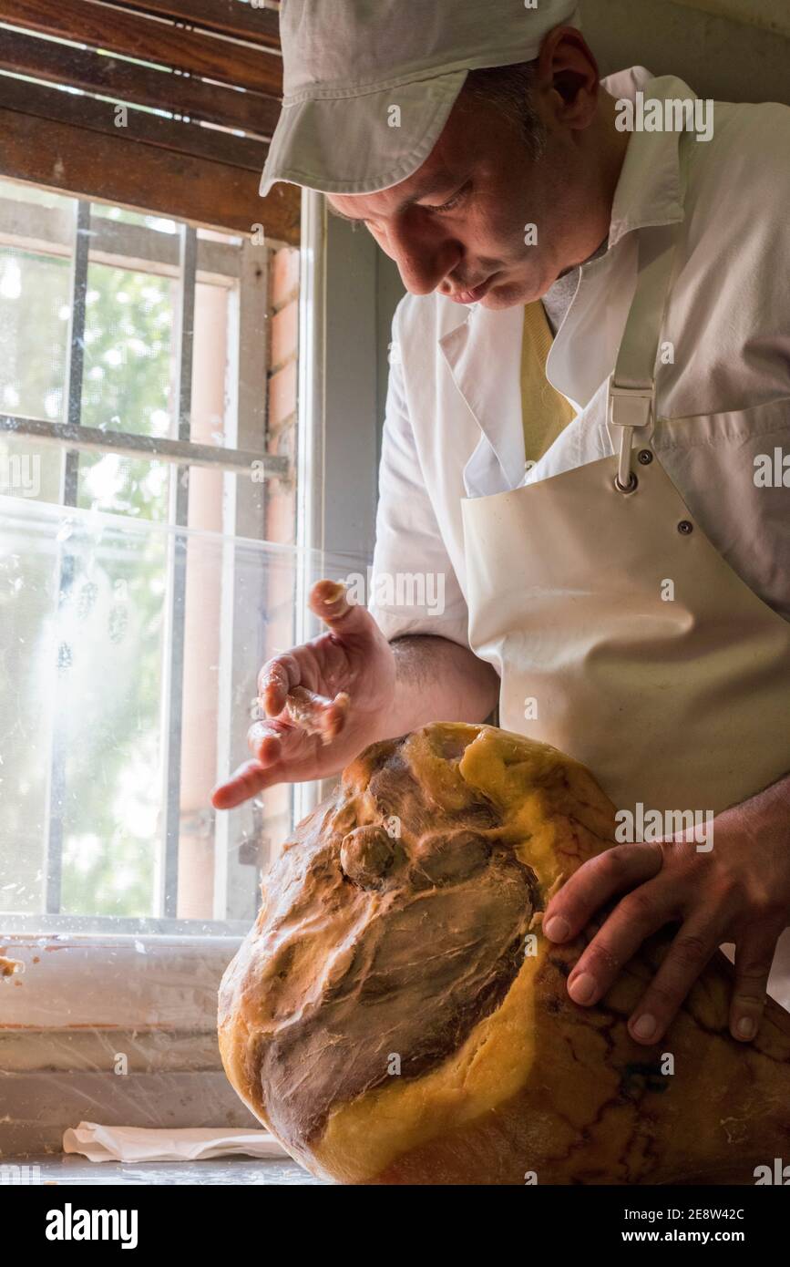 Un ouvrier dans une usine de jambon de parme ajoutant de la graisse à la main pour sceller la viande avant d'être mûri Banque D'Images