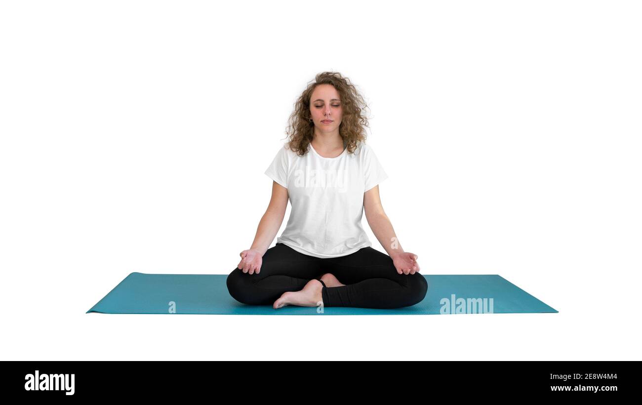 Jeune femme aux yeux fermés faisant du yoga sur un tapis bleu isolé sur fond blanc. La femme a des cheveux bouclés blonds. Banque D'Images