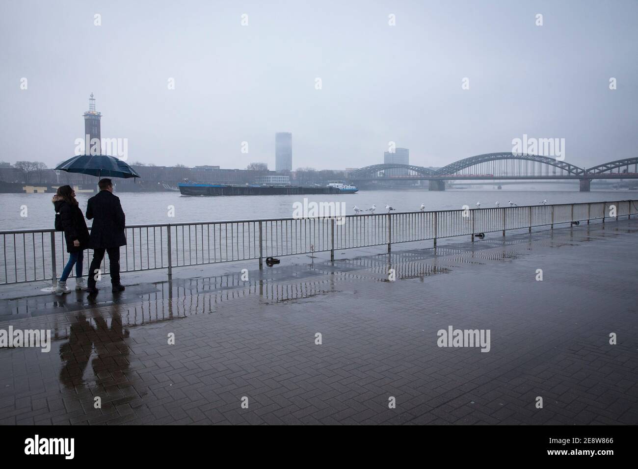 Un couple sous la pluie sur les rives du Rhin, en regardant vers le quartier de la ville Deutz et le pont Hohenzollern, Cologne, Allemagne. ein Paar BEI R. Banque D'Images