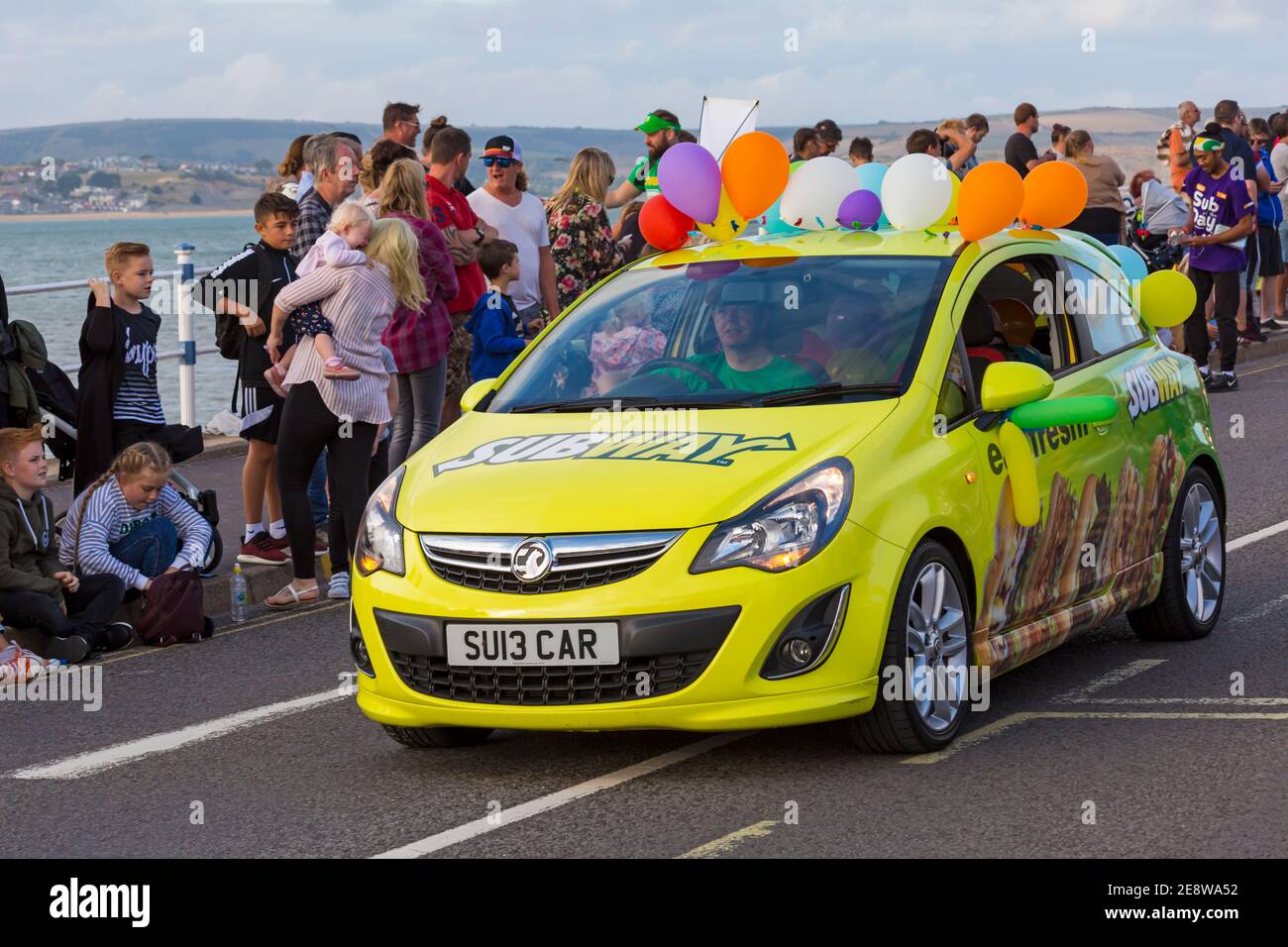 La voiture jaune de métro Vauxhall Corsa avec ballons participe au défilé de procession au Carnaval de Weymouth, Weymouth, Dorset au Royaume-Uni en août Banque D'Images