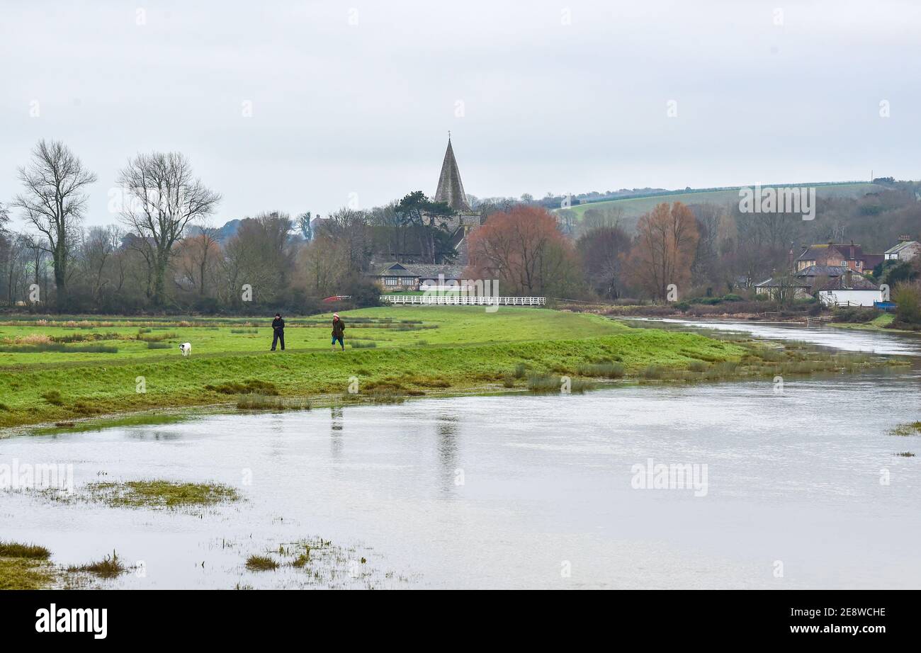 Brighton Royaume-Uni 1er février 2021 - marcheurs pour chiens au bord de la rivière Cuckmere à Alfriston près de Seaford dans East Sussex par une journée sombre et nuageux dans le Sud-est . Les niveaux d'eau de la rivière sont élevés avec les champs environnants étant inondés après des semaines de pluie durables à travers les mois d'hiver en Grande-Bretagne : crédit Simon Dack / Alamy Live News Banque D'Images