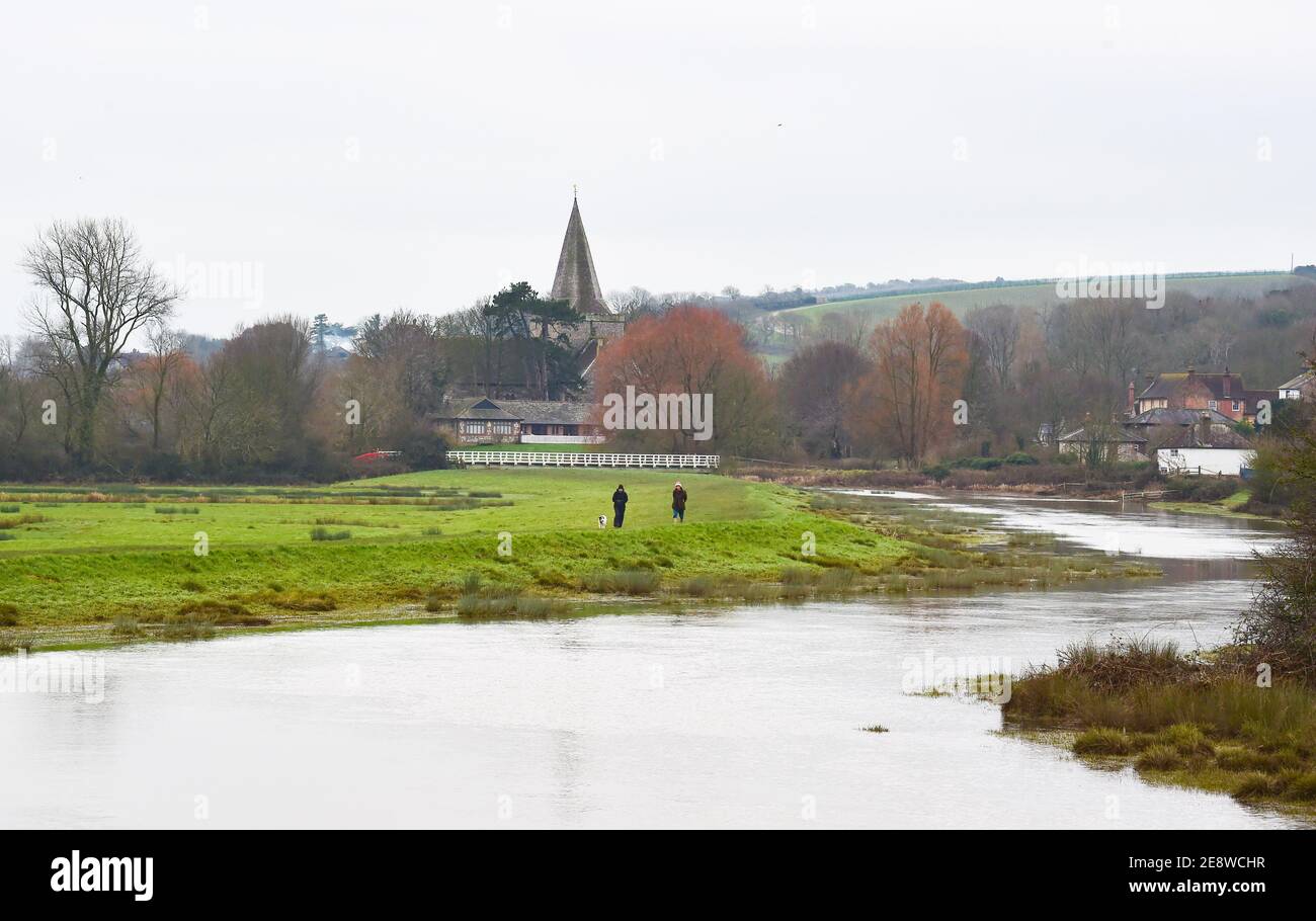 Brighton Royaume-Uni 1er février 2021 - marcheurs pour chiens au bord de la rivière Cuckmere à Alfriston près de Seaford dans East Sussex par une journée sombre et nuageux dans le Sud-est . Les niveaux d'eau de la rivière sont élevés avec les champs environnants étant inondés après des semaines de pluie durables à travers les mois d'hiver en Grande-Bretagne : crédit Simon Dack / Alamy Live News Banque D'Images